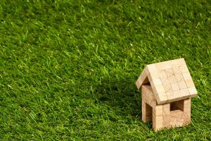 A small model home made of wood on the grass.