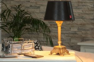 An old-style lamp on the desk in front of wall with stone decoration. 