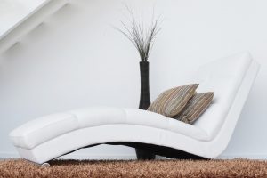 A modern white sofa and brown carpet.