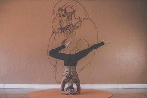 a girl doing yoga poses in front of a drawing on a wall