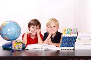 Two boys sitting at their desk in a classroom.