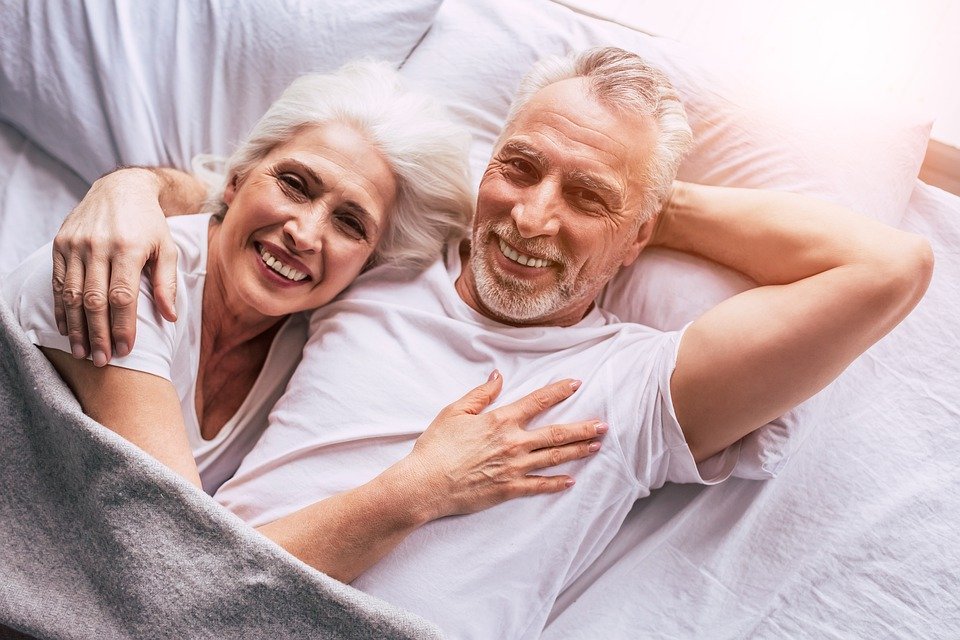 an elderly couple in bed, relaxing and enjoying life.