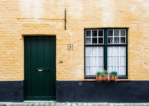 A yellow wall with a green door and window.