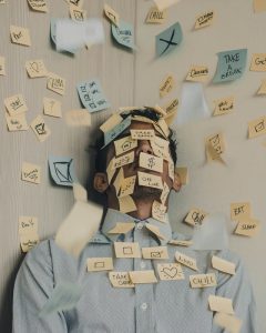 A stressed-out man covered with to-do post-its who's trying to find a way to reduce stress when buying a house.