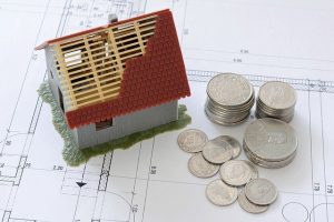 A small model house and some coins.