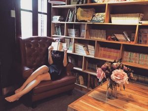 A woman reading a book on the sofa.