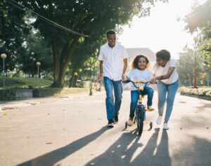 Parents teaching their child to ride a bike.