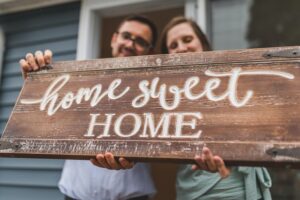 A couple holding "home sweet home" sign.