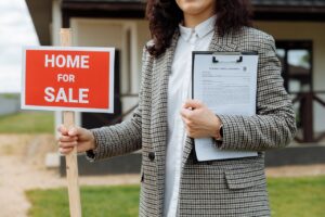 A realtor holding sign for sale and documents explaining what are mistakes to avoid when selling your Miami home.