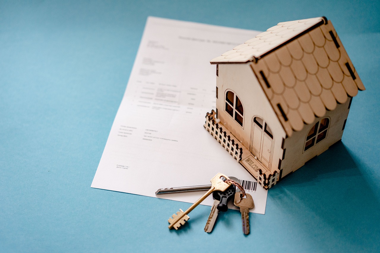 A contract, house keys, and a small wooden model house.