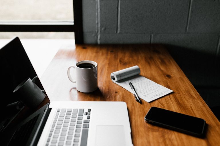 A laptop, phone, notebook and a pen for house hunting in New Hampshire 