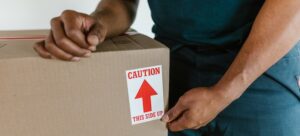 A man taping a cardboard moving box.