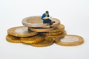 A pile of coins and a small figurine of a man on it.