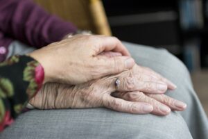 Two senior people holding hands.