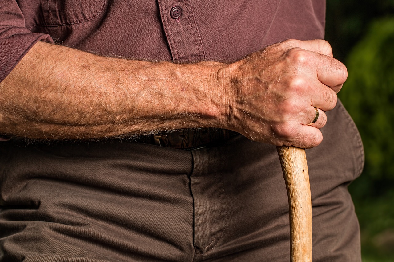 An elderly man holding a walking stick.